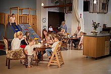 Kindercafe Kindercafe: Kinder sitzen am Tisch mit Ihren Eltern. es wird gegessen und getrunken. Ein Mädchen ist gerade auf der Rutsche.