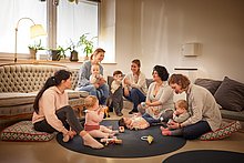 Das Anna Kindercafe: Mütter sitzen auf gemütlichen Kissen auf dem Boden, um mit ihren Kindern und Babys zu spielen.
