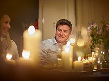 Event-Location Das Anna – Portrait von lächelndem Mann aus niedriger Perspektive flackernden Kerzen von der anderen Seite des Tisches aus.