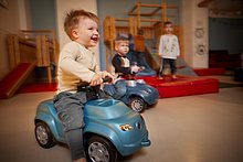 Kindercafe Essen | Spielbereich Kindercafe Essen – Kleine Jungs toben im Spielbereich, zwei Jungs flitzen lachend auf Bobbycars umher.