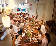 Event-Location – Das Anna Abend Event Kindercafe Essen: Erwachsene, Kinder und Babys an großen Tisch feiern Geburtstag. Es wird gegessen, gelacht und gespielt.